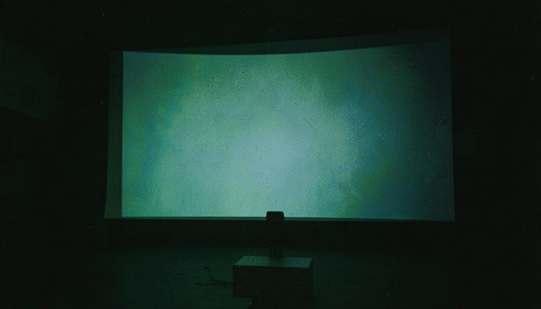 Analogna filmska fotografija modernog audiovizualnog sustava u tamnoj dvorani s plavkastim osvjetljenjem i velikim ekranom