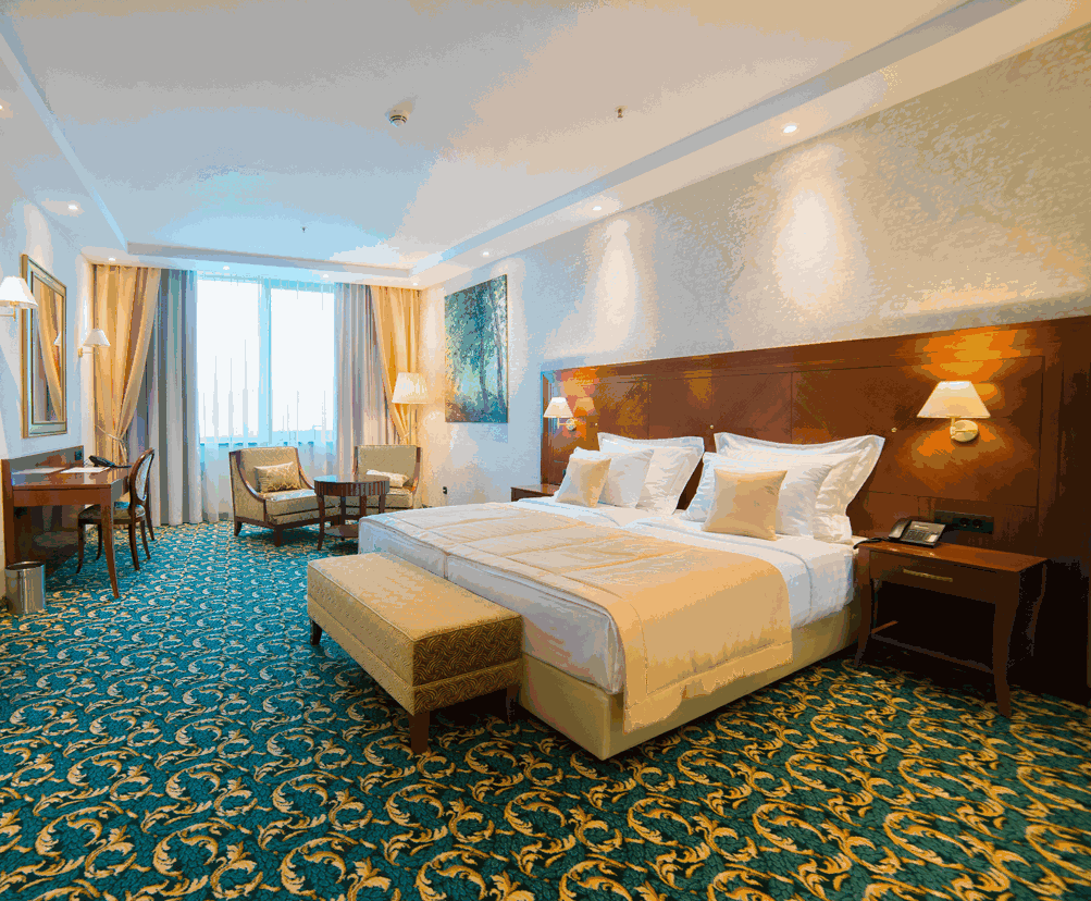 Hotelska soba s velikim krevetom, radnim stolom, foteljom i prozorom s zavjesama, topao i ugodan ugođaj